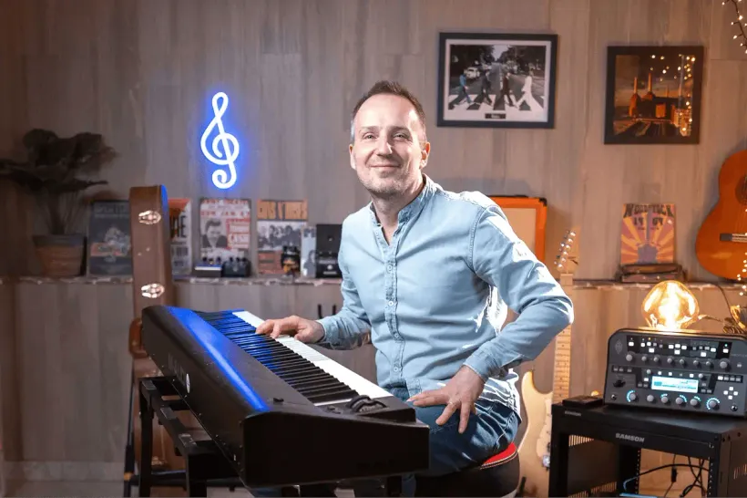 Cyrille, pédagogue en chef de MyPianoPop, assis à son piano, une main posée sur le clavier